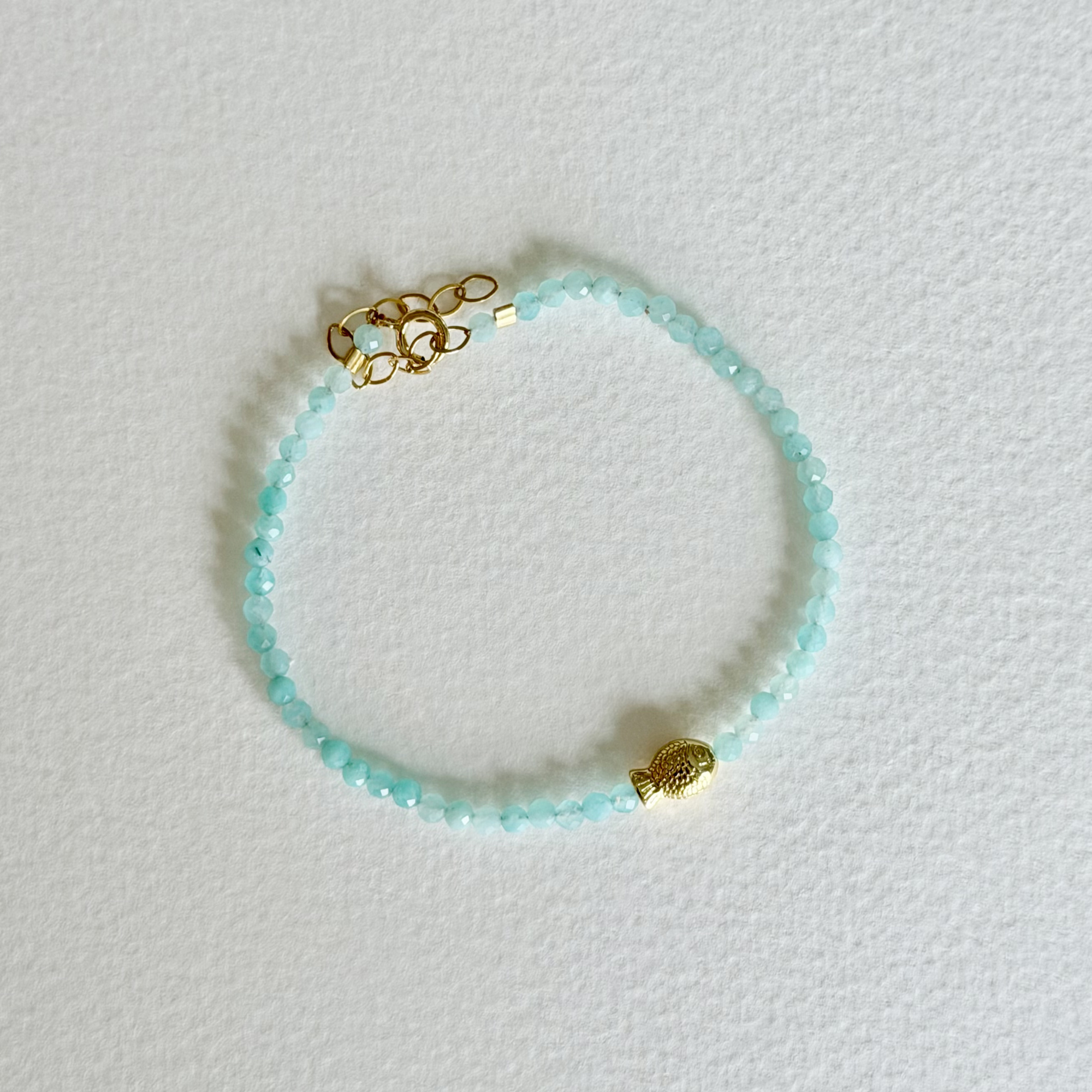 Turquoise beaded bracelet with gold accents on a light gray background