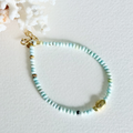 Turquoise beaded bracelet with gold accents on a light gray background