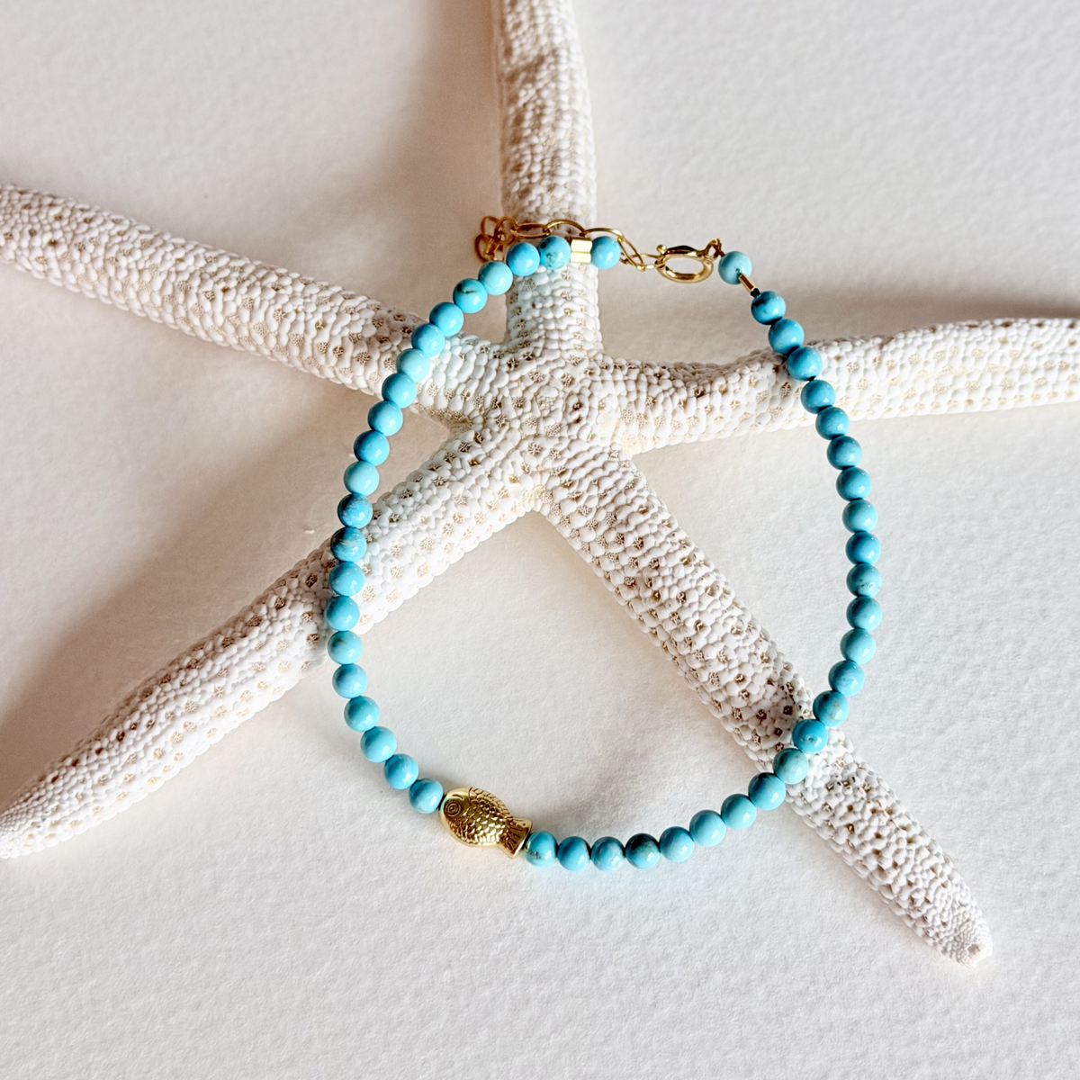 Turquoise beaded bracelet with gold accents on a starfish