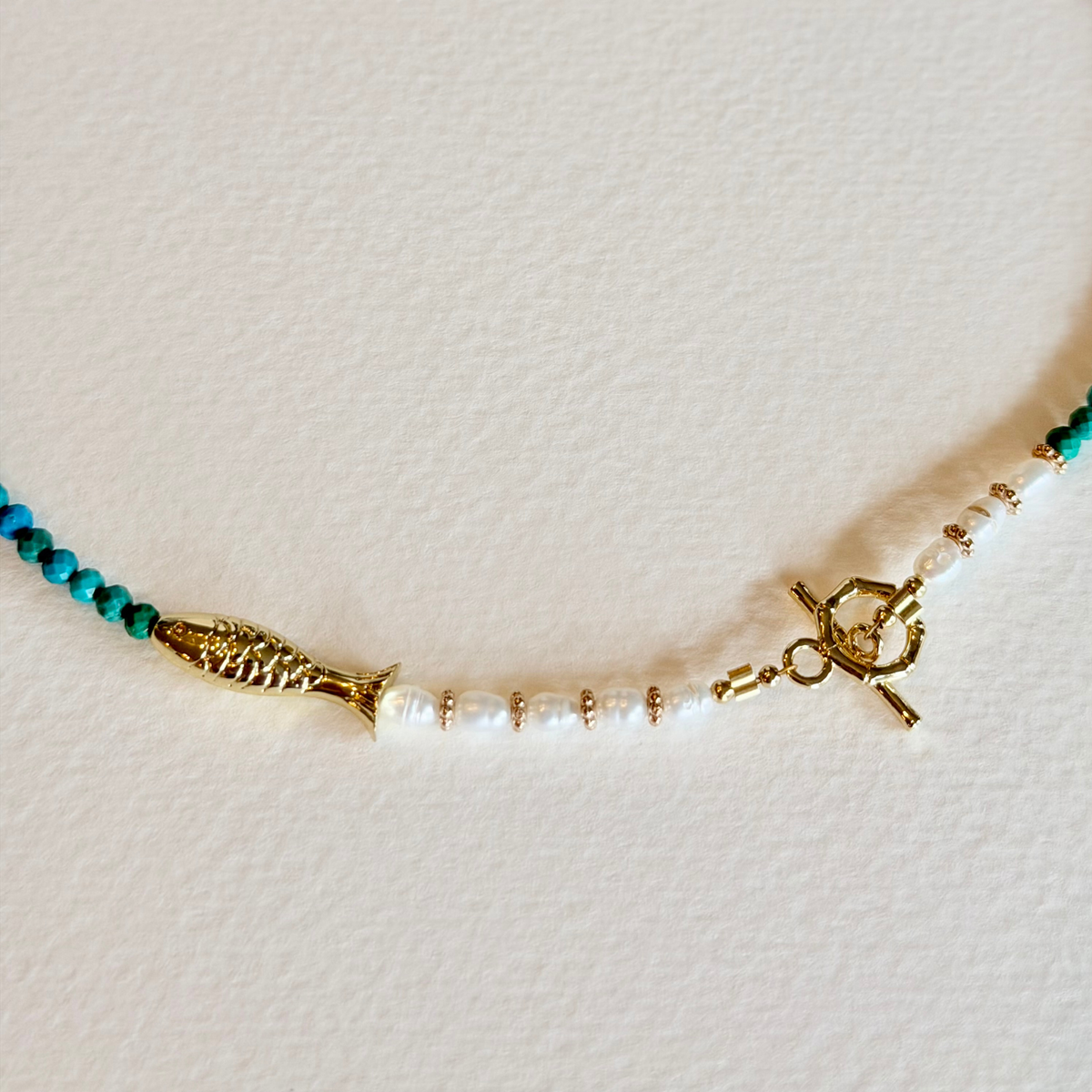 Necklace with gold clasp and beads on a light background