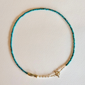 Turquoise beaded necklace with gold clasp on a light background