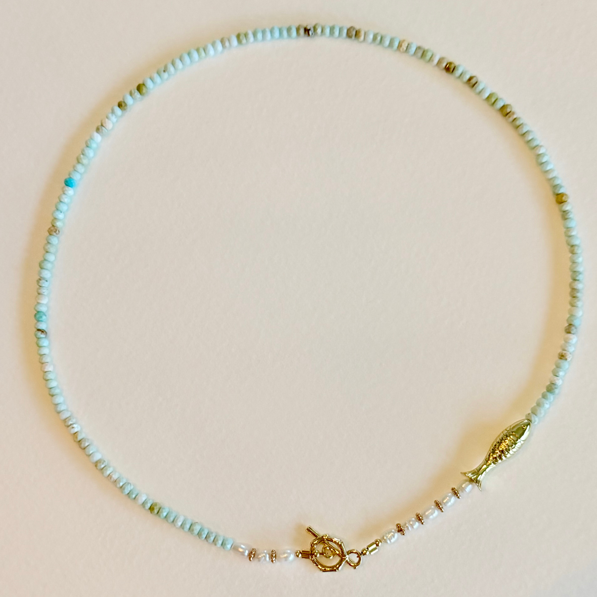 Necklace with light blue beads and gold accents on a beige background