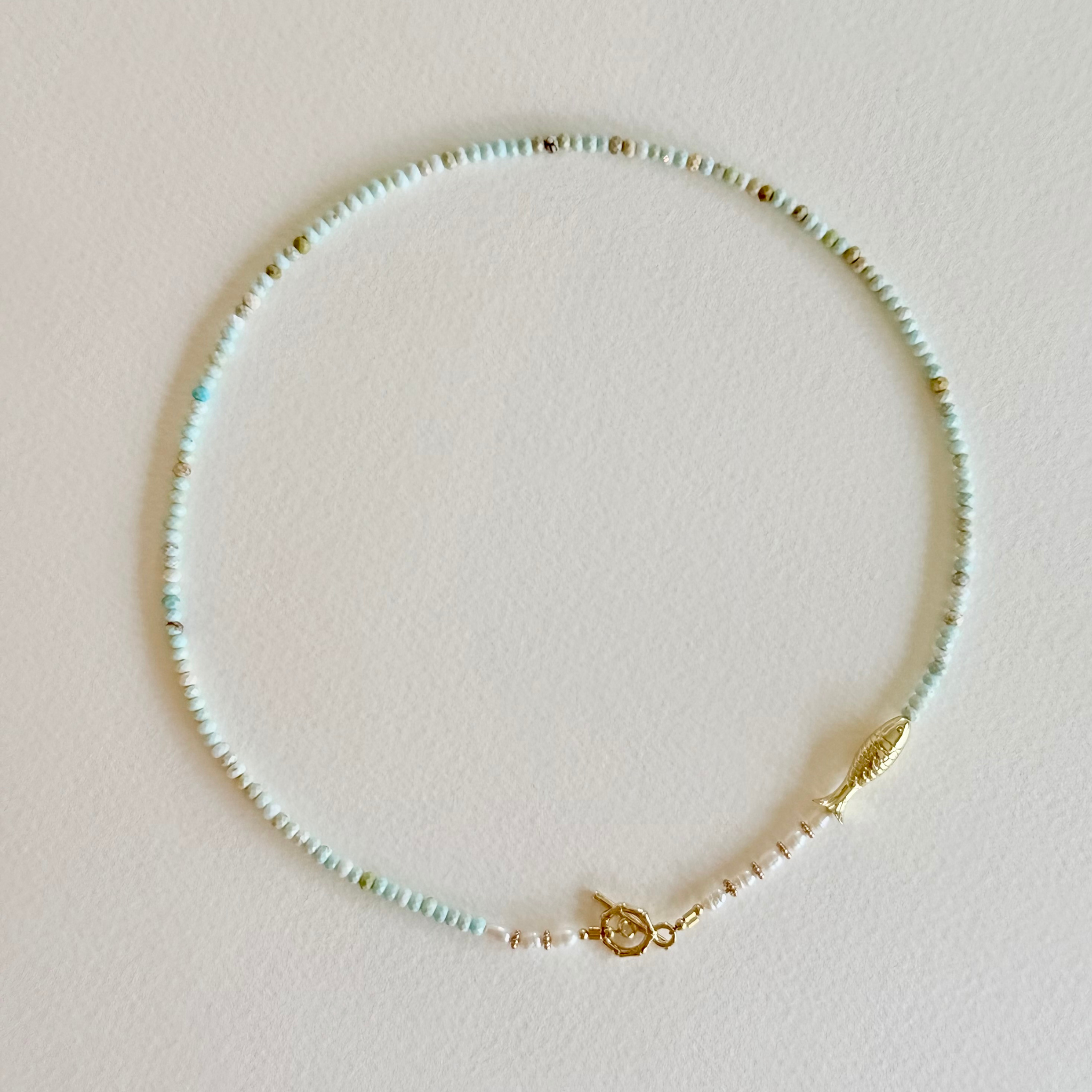 Beaded necklace with a gold clasp on a light pink background