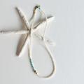 A white textured starfish-shaped pendant necklace with a matching beaded chain featuring turquoise and gold beads, displayed on a white background.