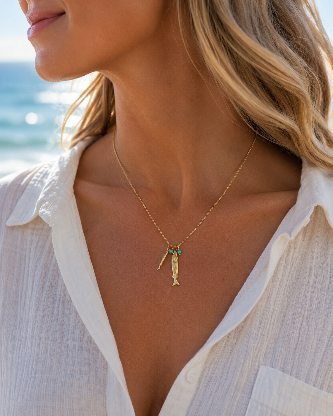 Woman wearing a handmade 14k gold-filled coastal fish necklace with turquoise gemstones by Marie & Oakley.
