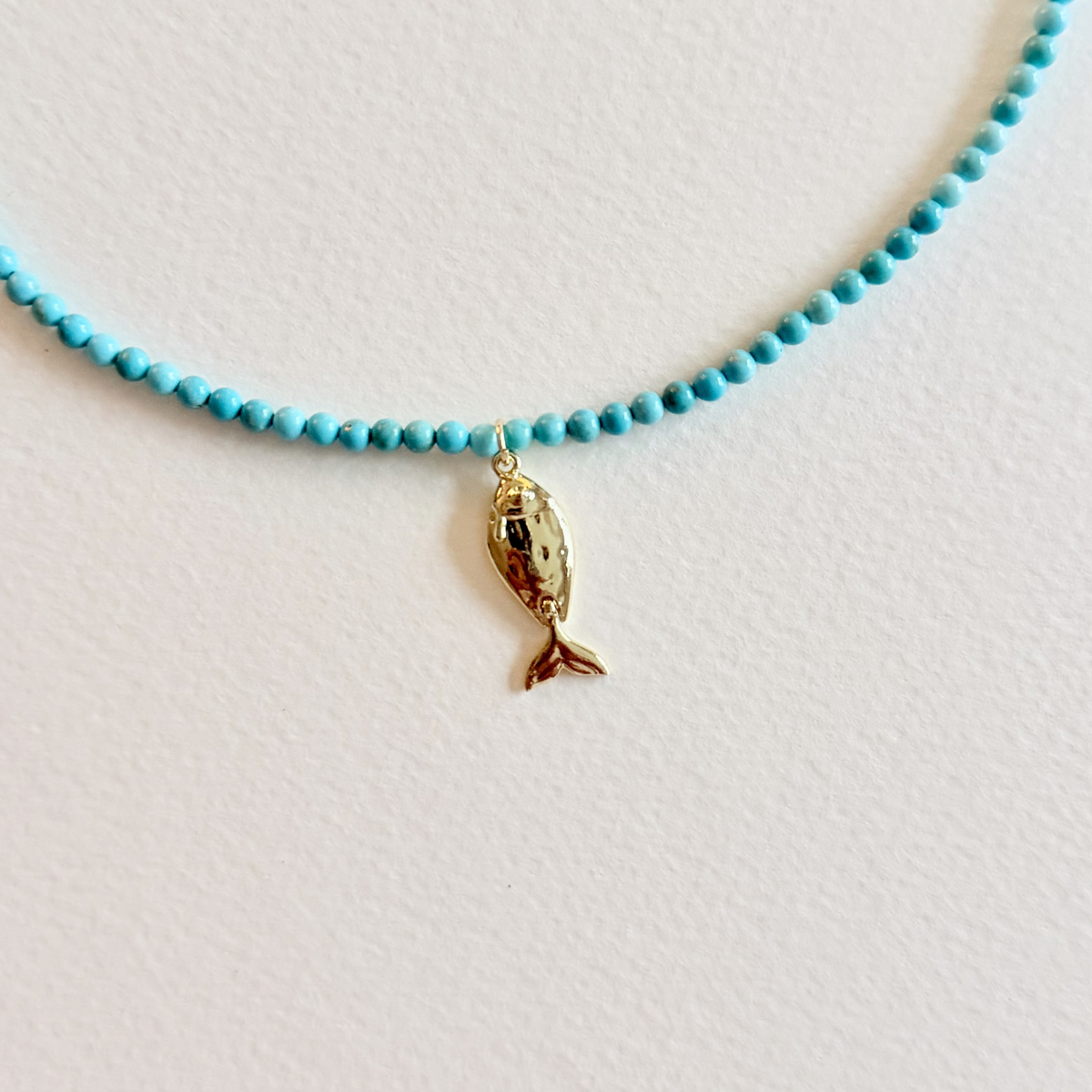 Little Catch Smooth Turquoise Necklace on light background showing the fish pendant close up
