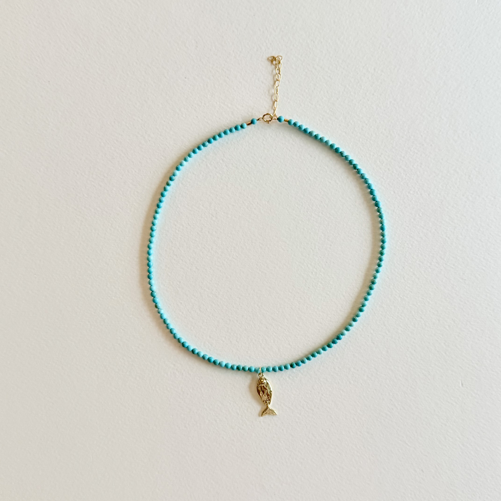 Little Catch Smooth Turquoise Necklace on light textured paper.