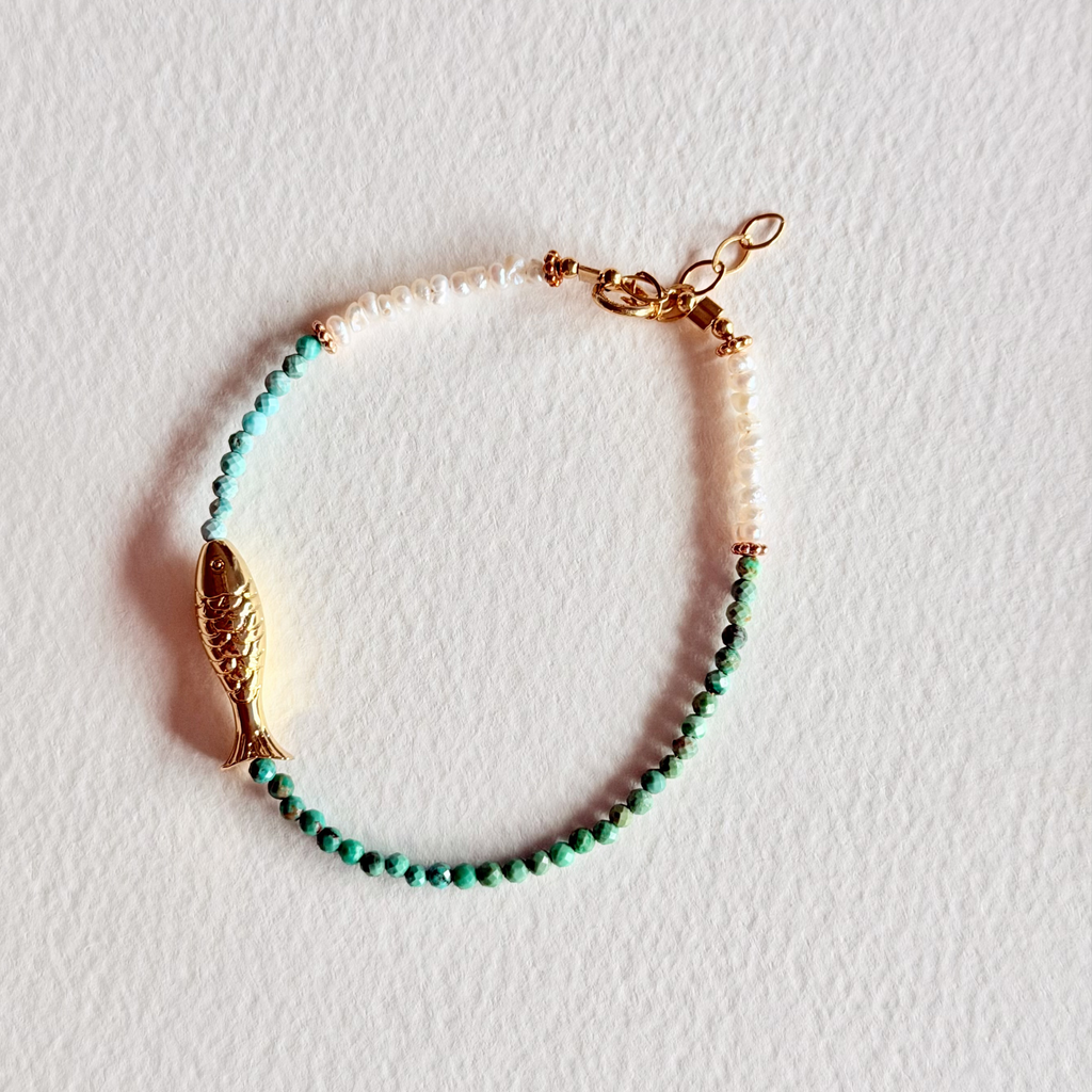 Bracelet with turquoise beads and gold accents on a light background