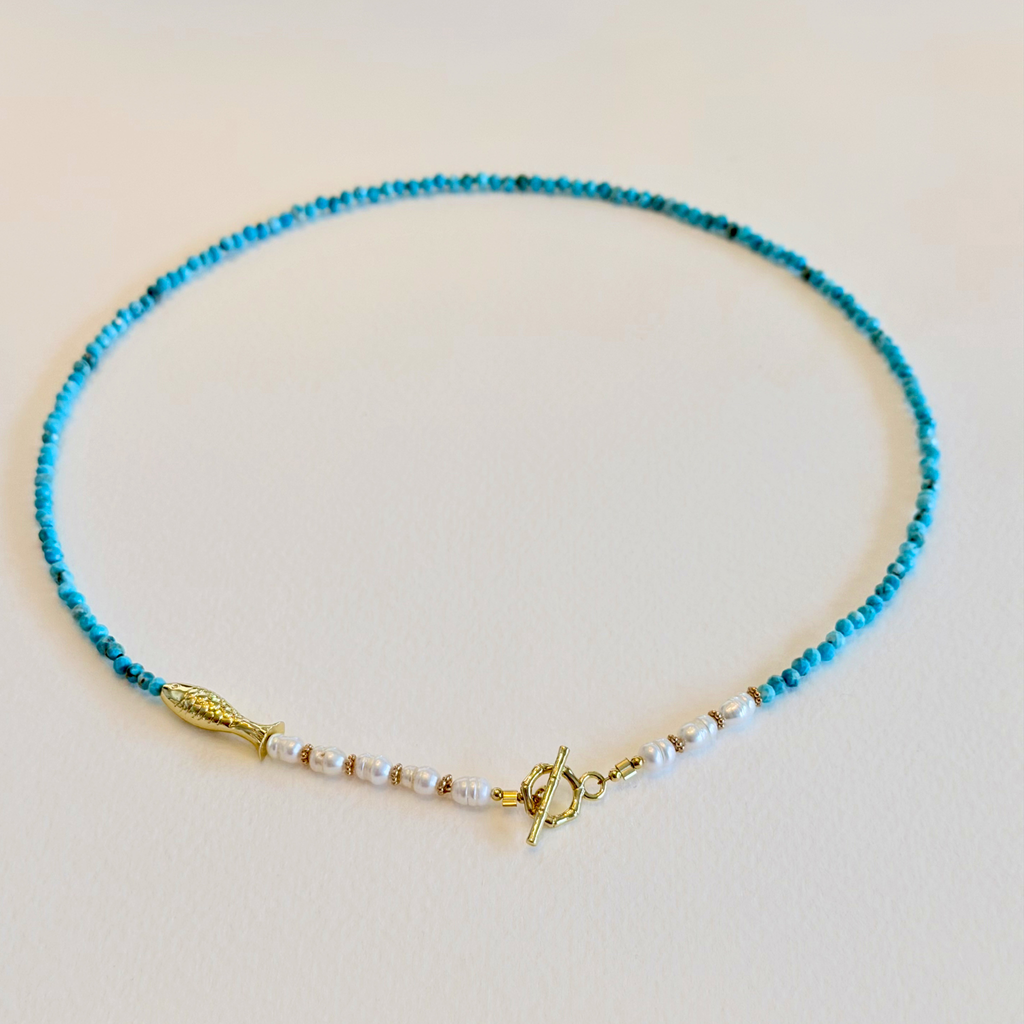 Necklace with blue beads and gold clasp on a light background