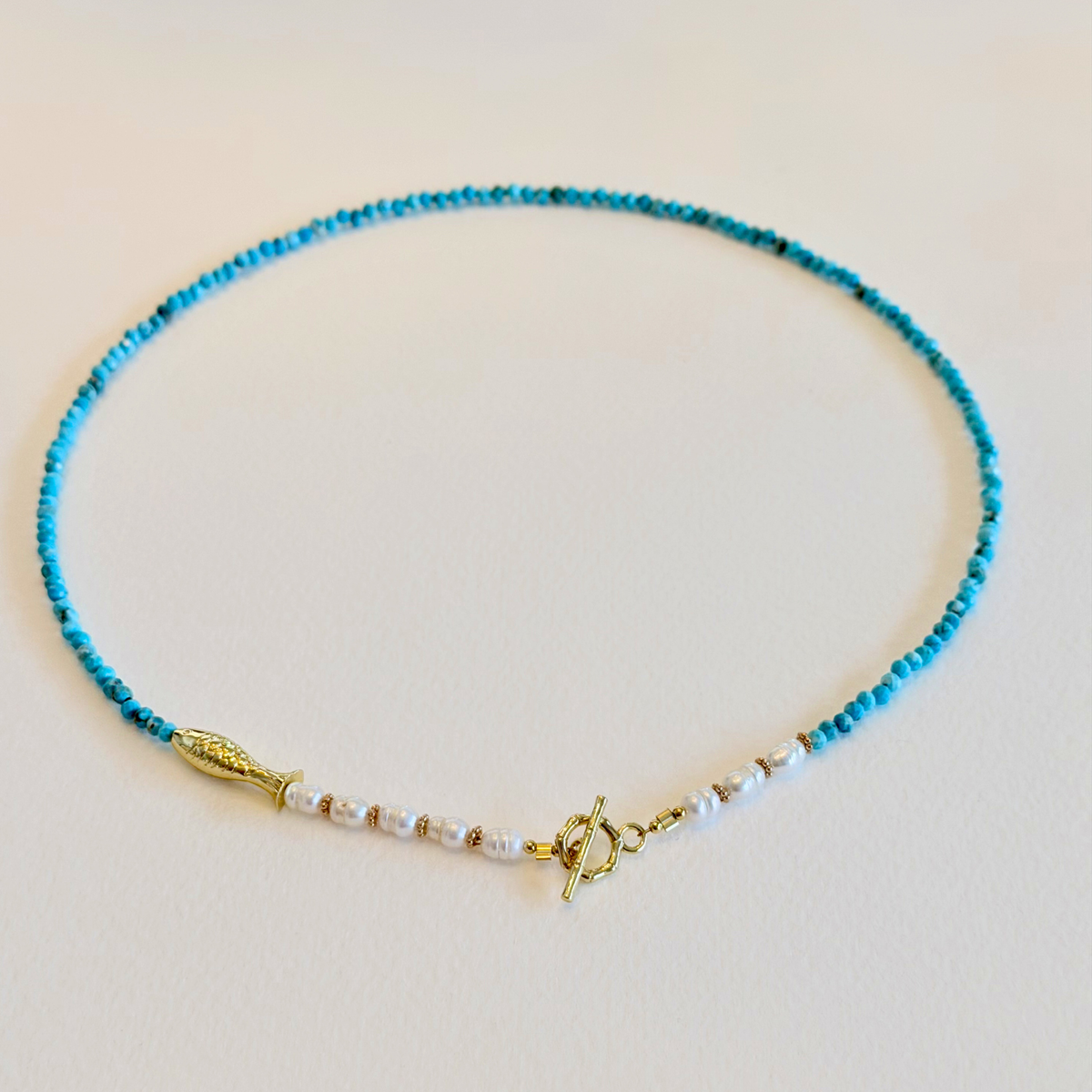 Necklace with blue beads and gold clasp on a light background