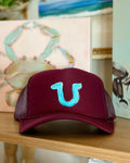 Burgundy trucker hat featuring a hand-painted turquoise horseshoe, a playful coastal cowgirl design by Marie & Oakley.