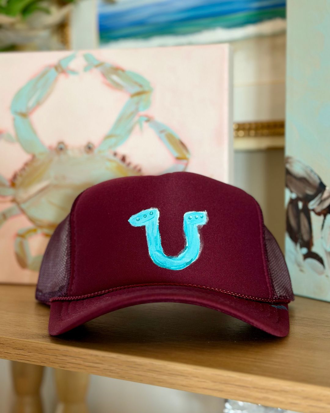 Burgundy trucker hat featuring a hand-painted turquoise horseshoe, a playful coastal cowgirl design by Marie & Oakley.