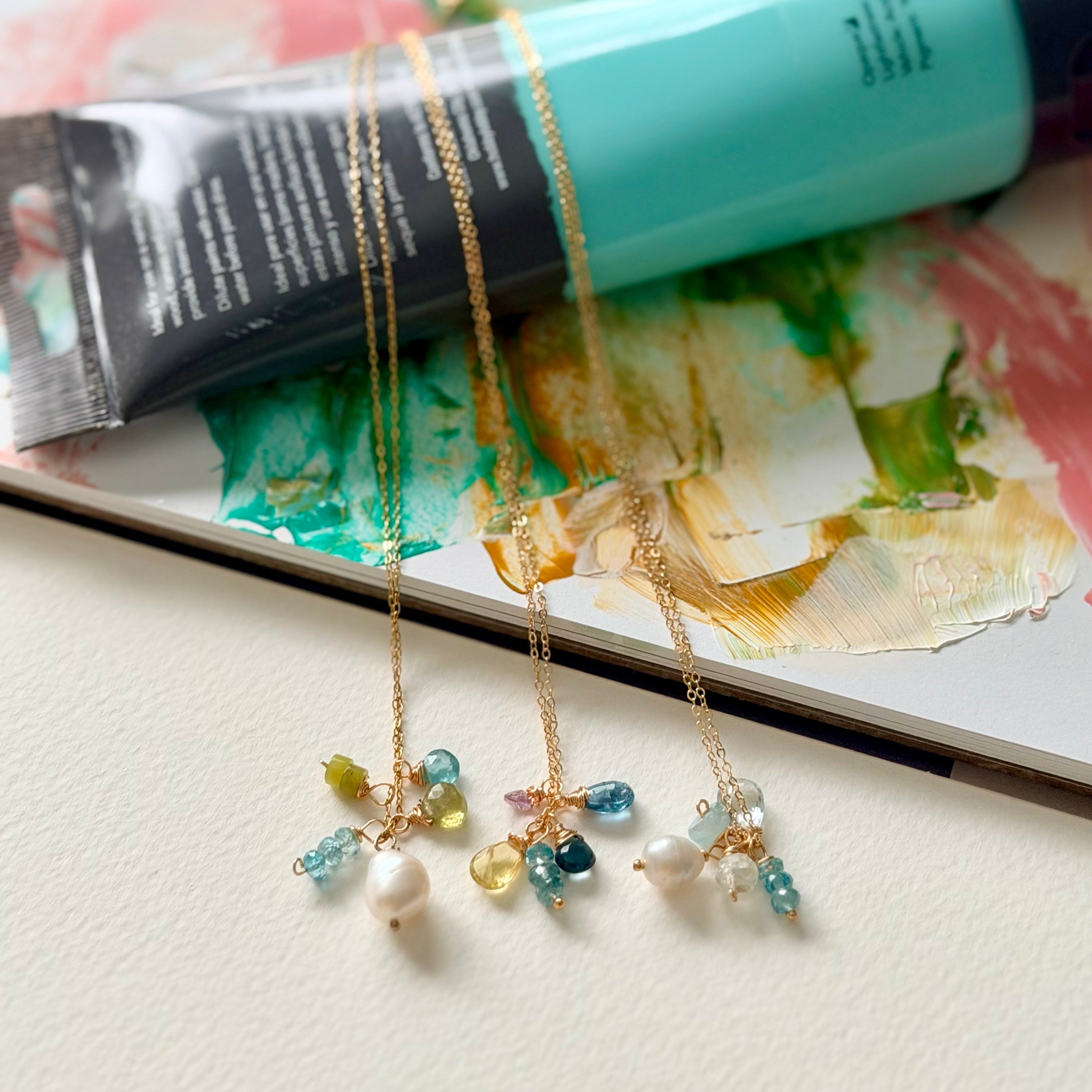 Two gold necklaces with colorful beads on a floral magazine background