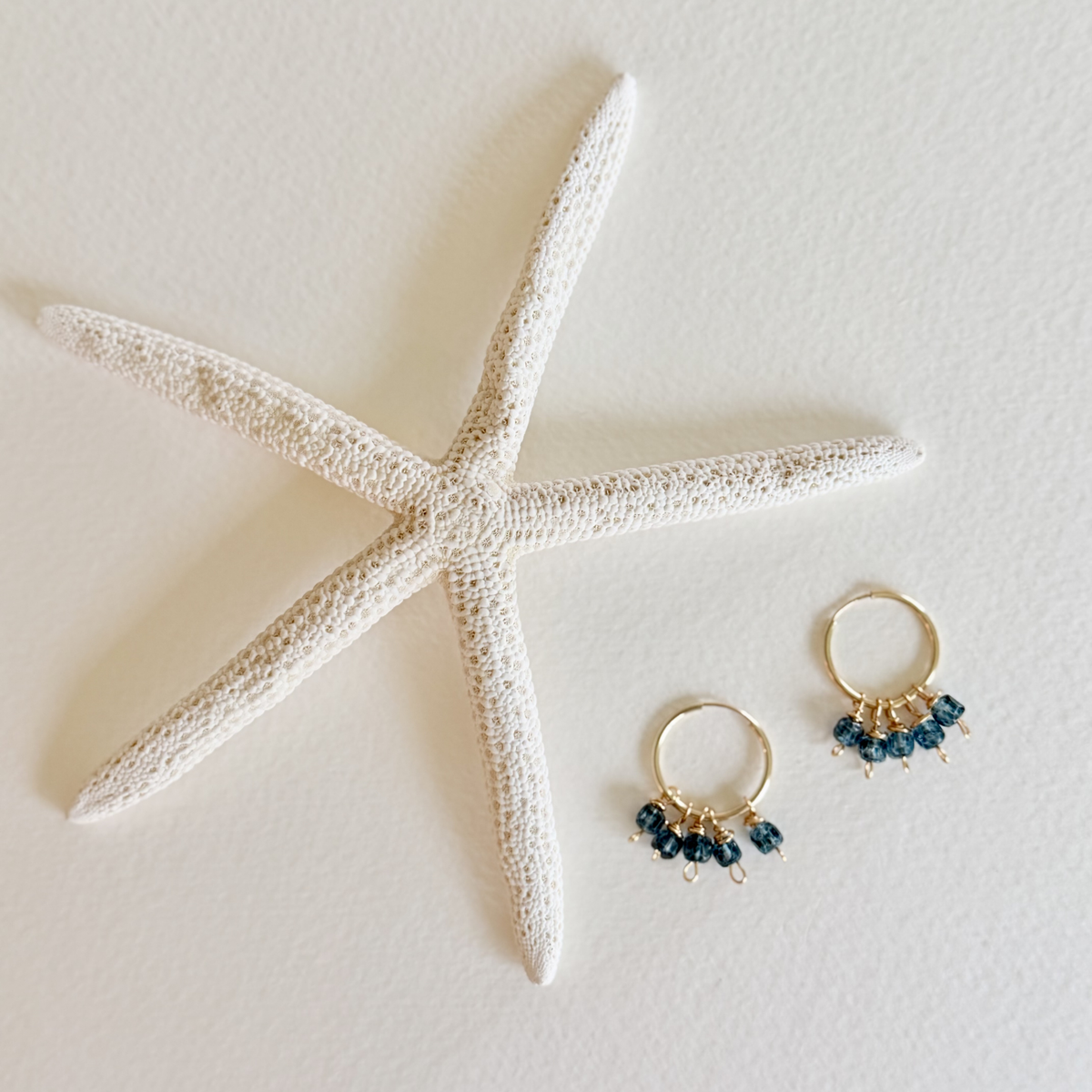 Gold hoop earrings with blue beads on a starfish