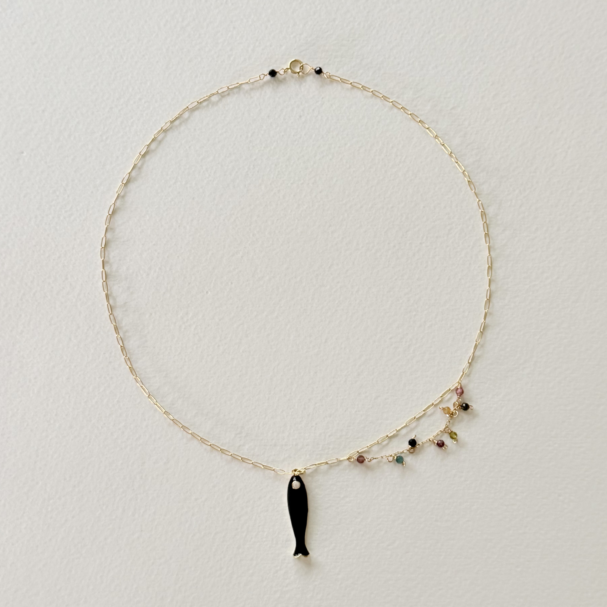 Necklace with a black fish pendant on a light gray background