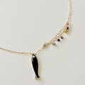 Necklace with a black fish pendant and multicolored beads on a light gray background