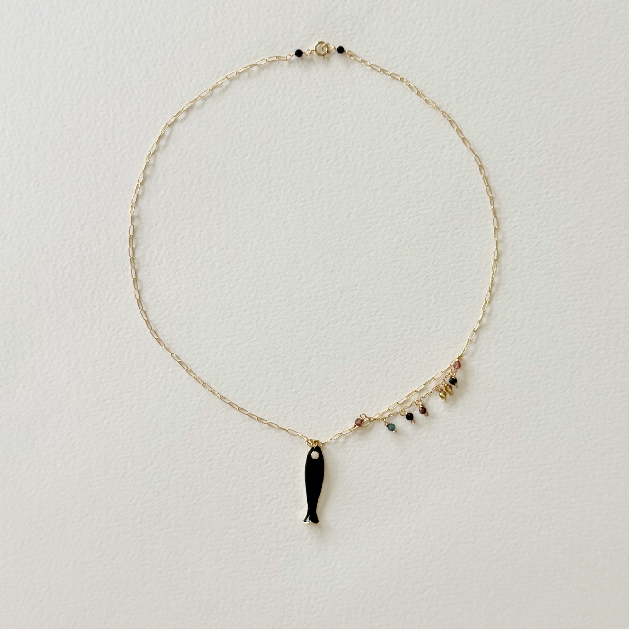 Necklace with a black fish pendant on a light gray background