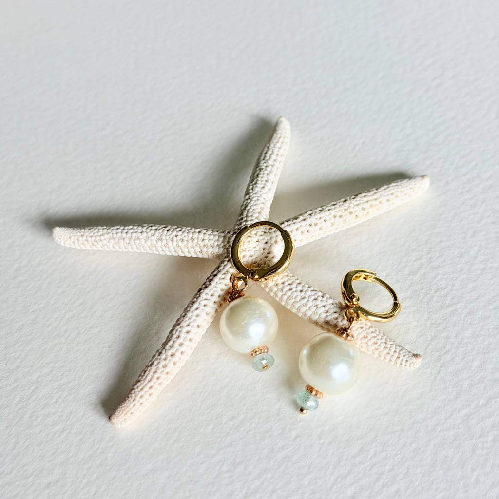 Pair of earrings with pearl-like beads and gold accents on a starfish.