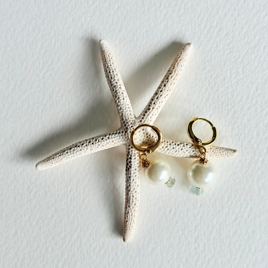 Gold earrings with pearls on a starfish against a light background