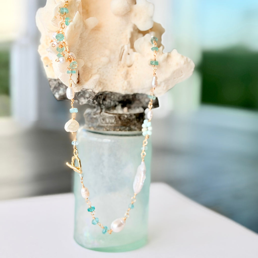 Decorative arrangement with coral, beads, and a small bottle on a blurred background