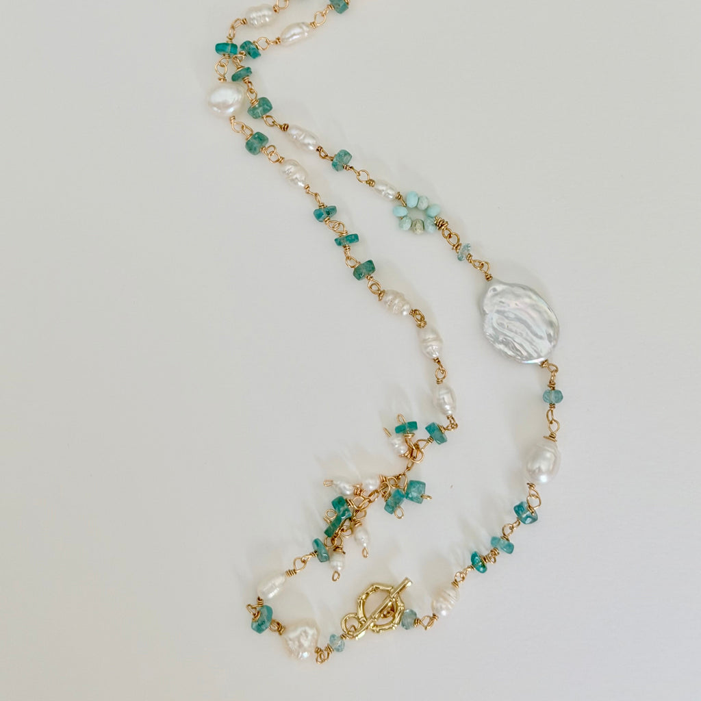Necklace with pearls and green beads on a light gray background