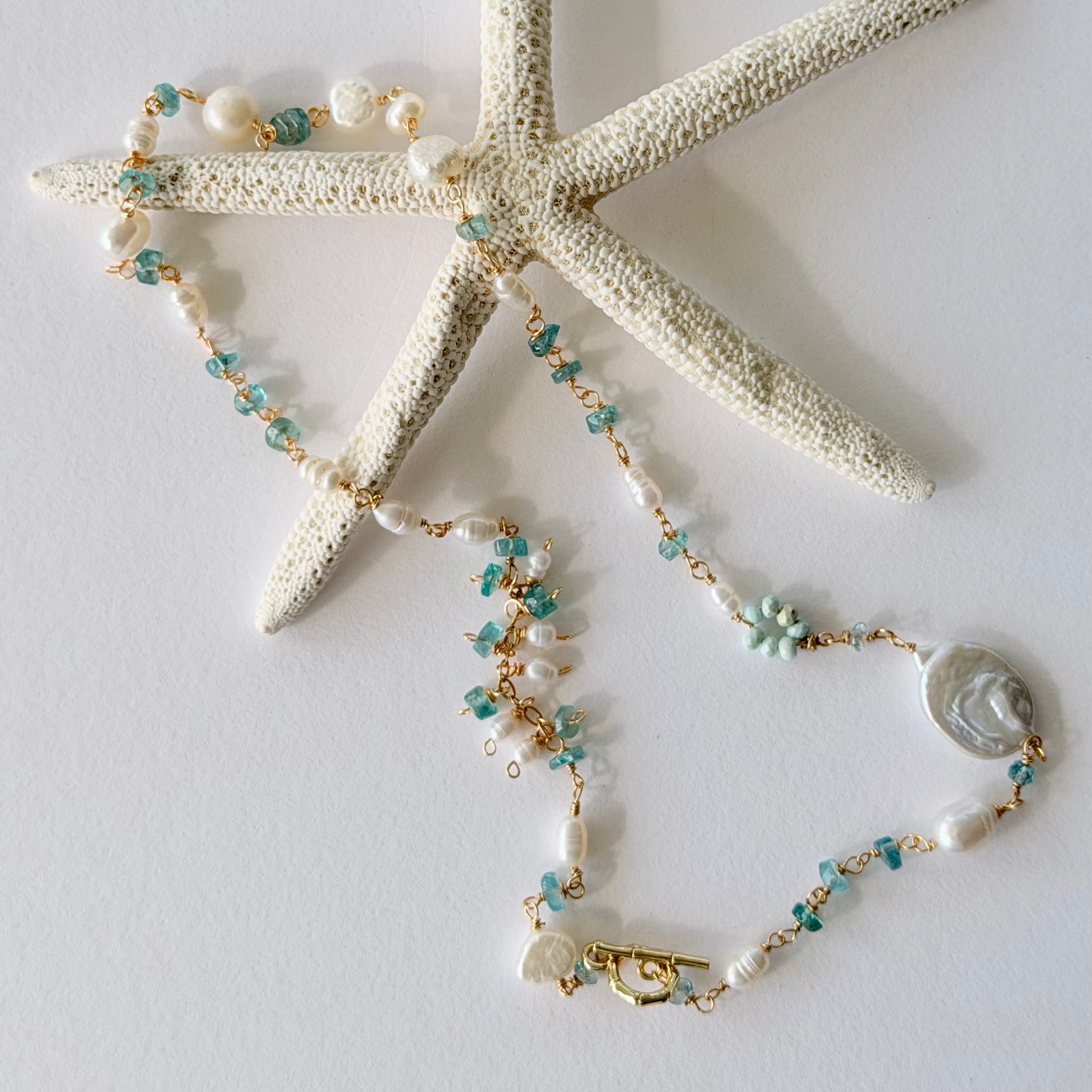 Necklace with pearls and blue beads on a starfish against a light background