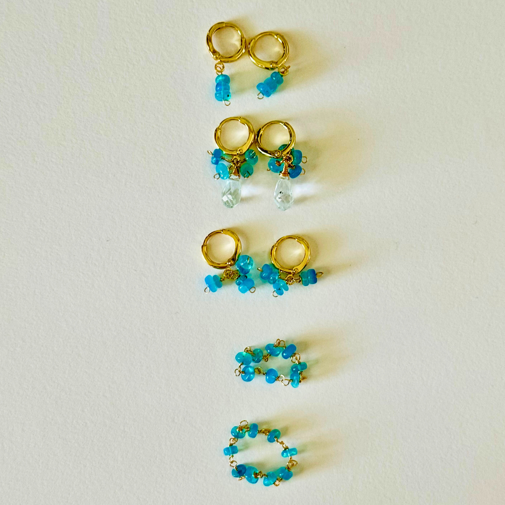 Gold and turquoise huggie earrings on a light background