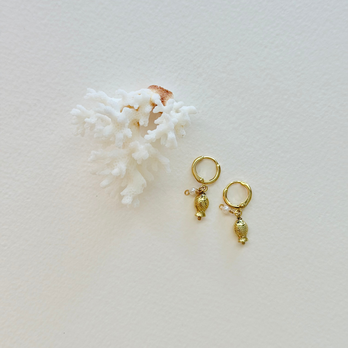 Gold earrings with charms on a white background