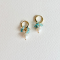 Pair of gold hoop earrings with turquoise beads and pearls on a light gray background