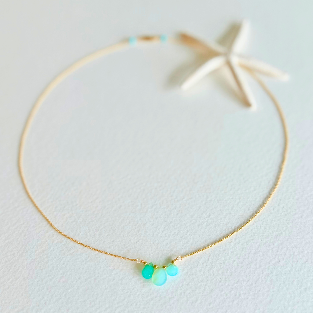 Gold necklace with turquoise beads on a light background