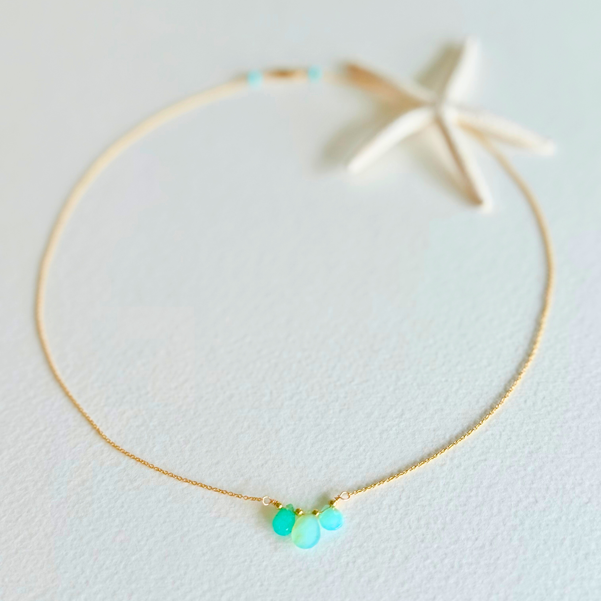 Gold necklace with turquoise beads on a light background