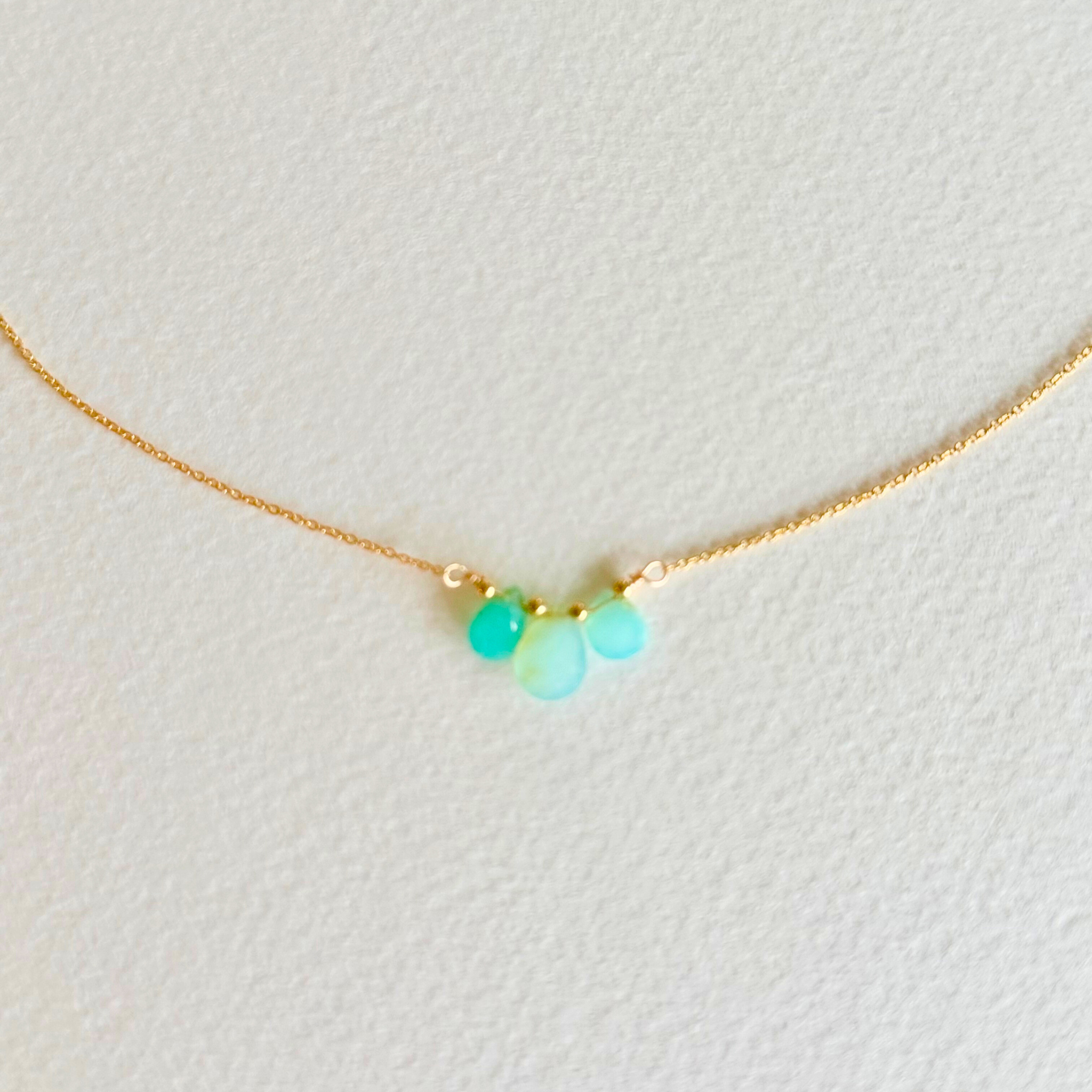 Gold necklace with turquoise beads on a light background