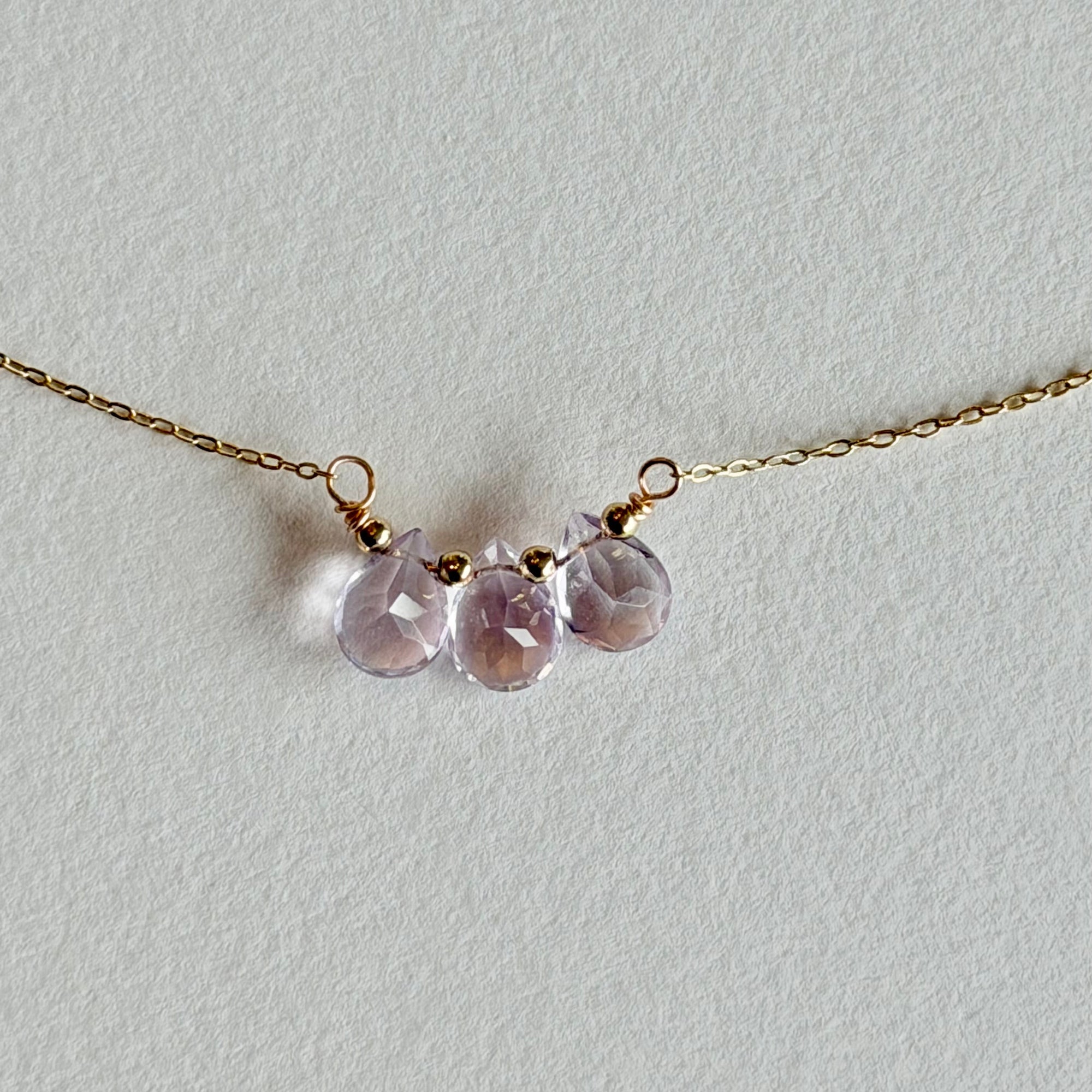 Necklace with pink teardrop-shaped gemstones on a light gray background