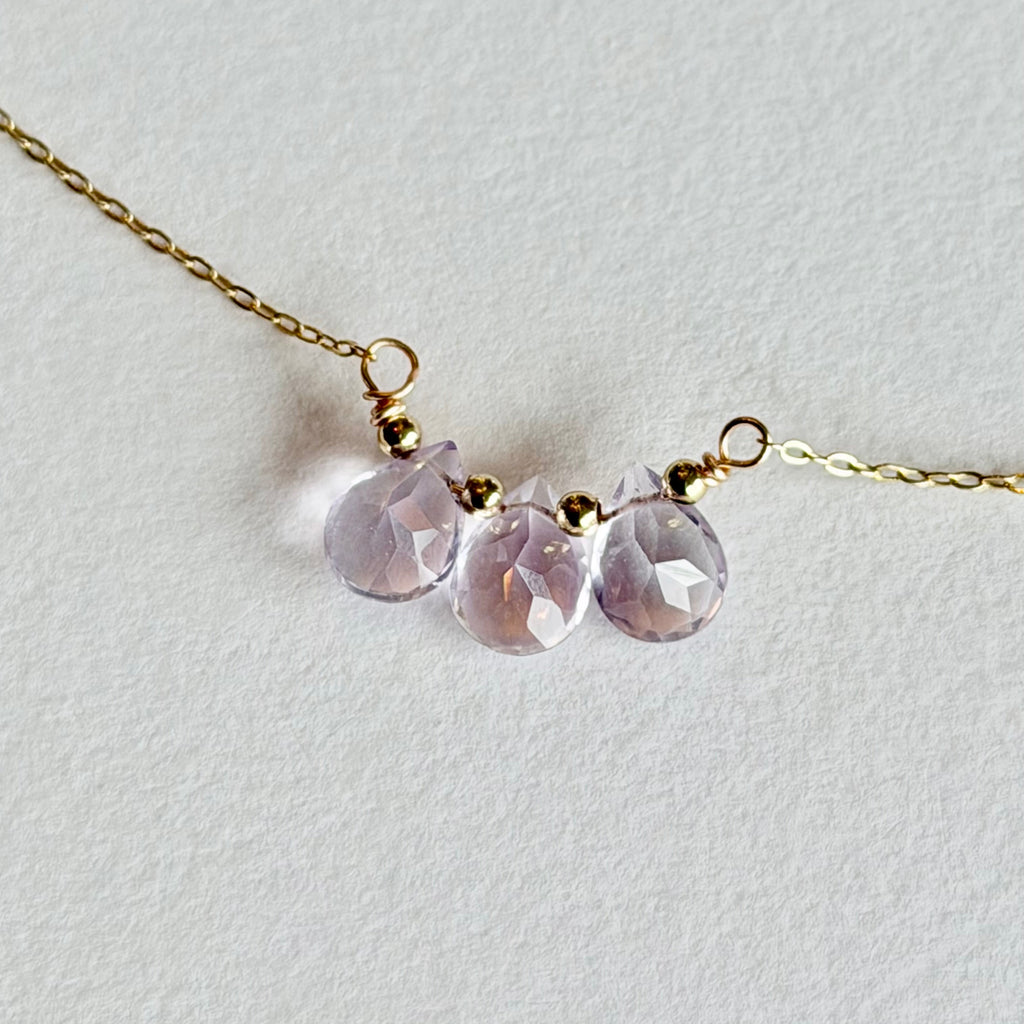 Necklace with three pink gemstones on a light gray background
