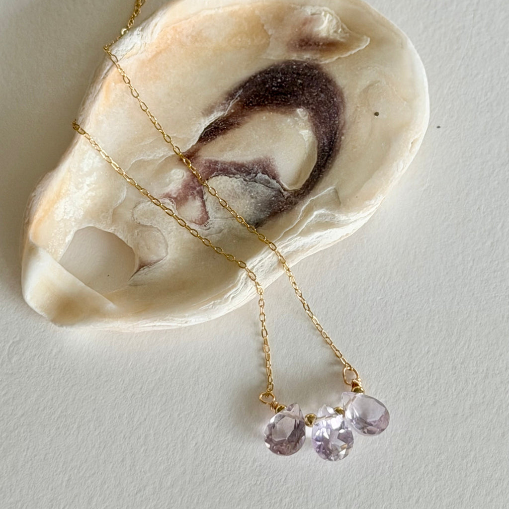 Necklace with purple beads on a shell against a light background