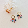 Gold hoop earrings with multicolored beads on a light background