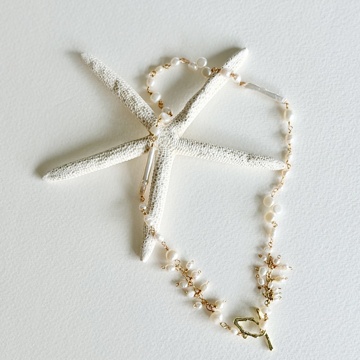Necklace with starfish and pearl details on a light gray background