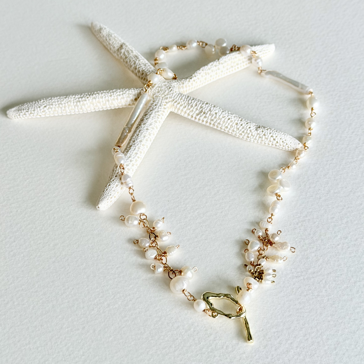 Necklace with gold and pearl details on a light gray background