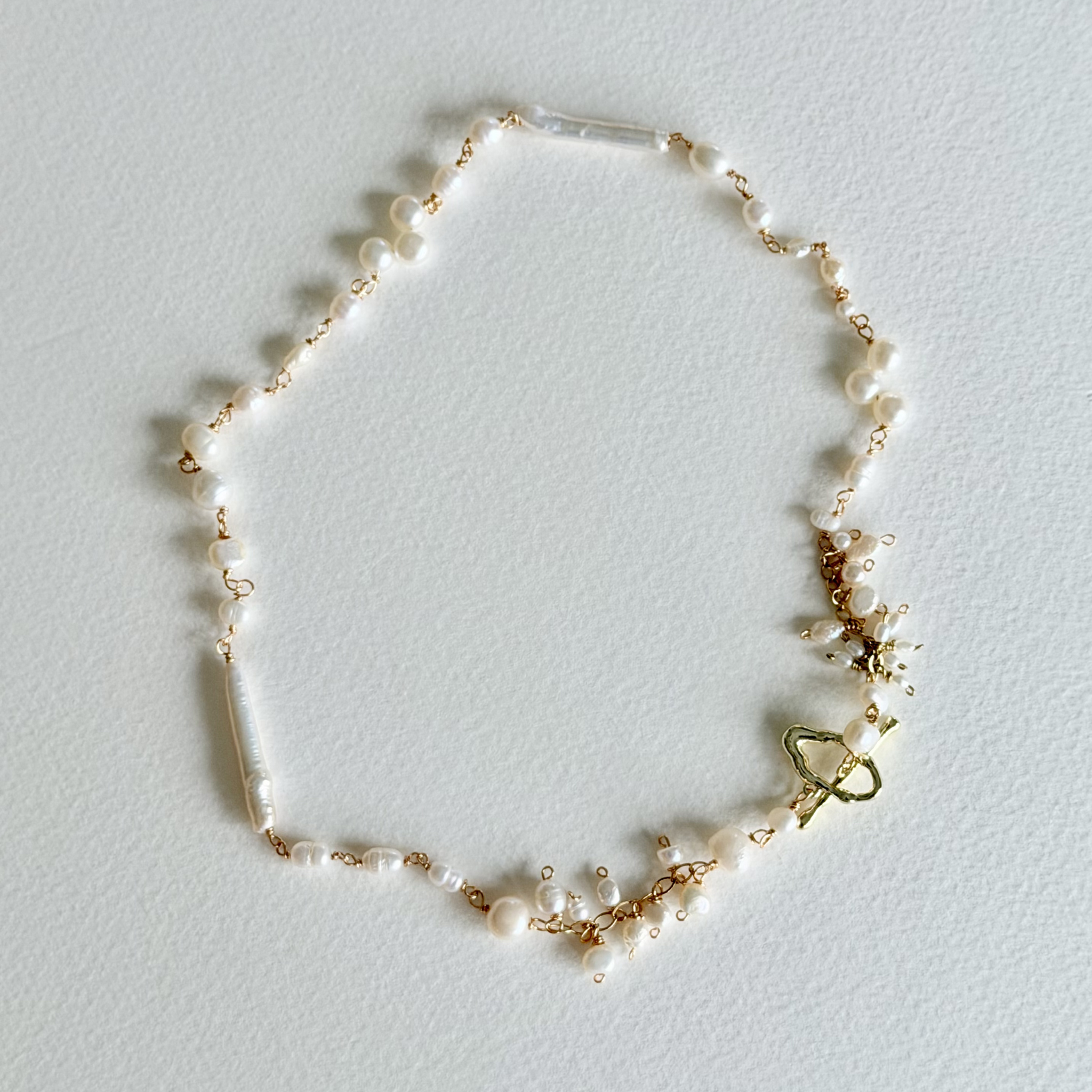 Delicate pearl necklace with gold accents on a light gray background