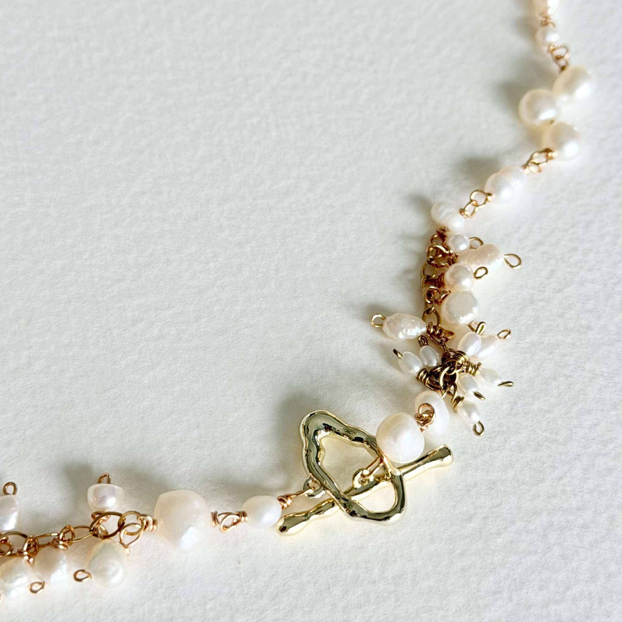 Pearl bracelet with gold clasp on a light gray background
