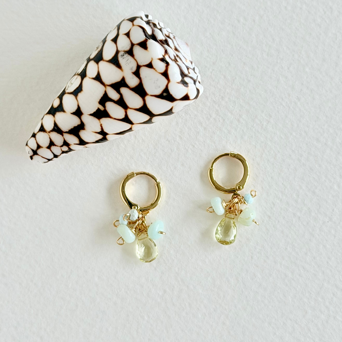 Gold earrings with clear gemstones on a light gray background