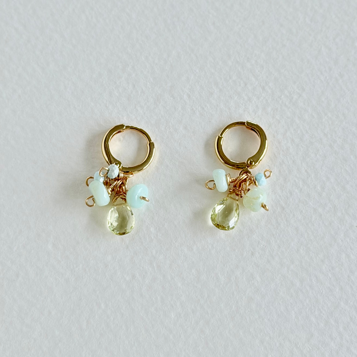 Gold hoop earrings with small gemstones on a light gray background