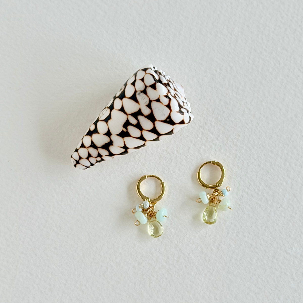 Pair of gold earrings with light green beads on a white background