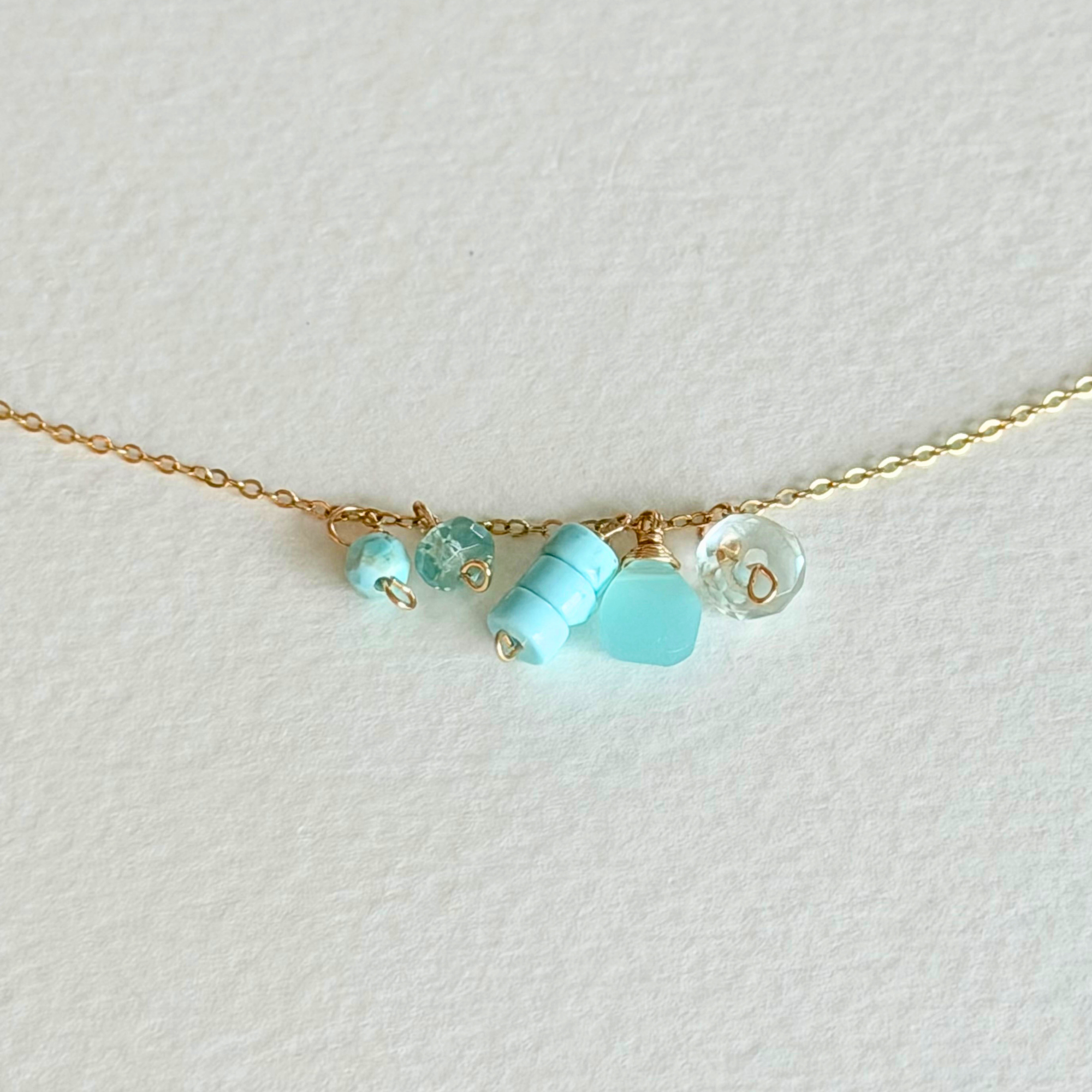 Delicate gold necklace with turquoise beads on a light background