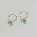 Gold hoop earrings with turquoise beads on a light gray background