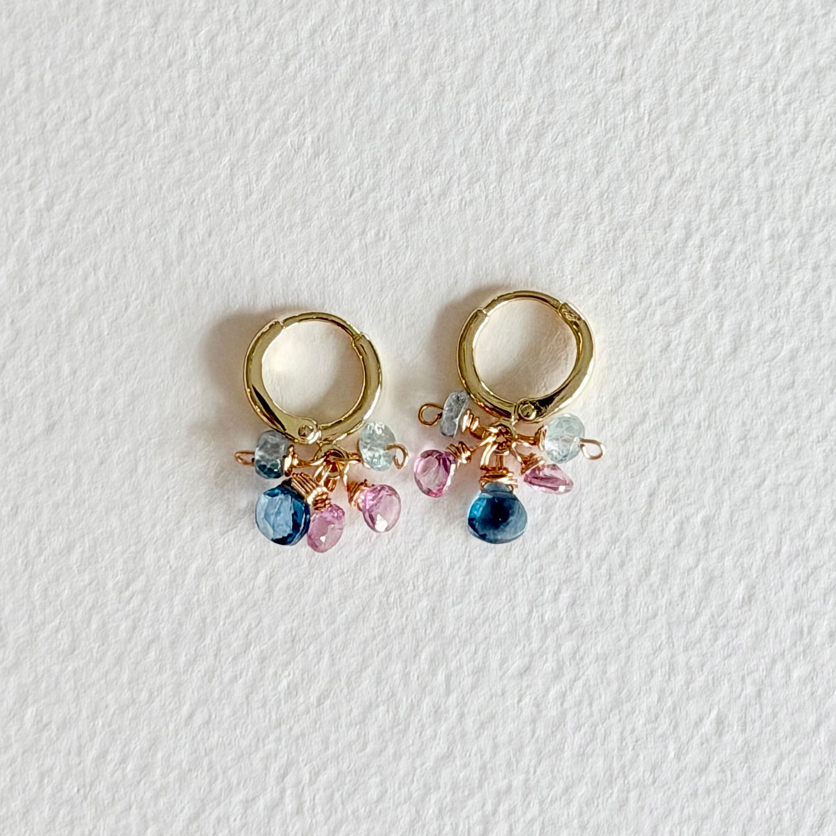 Gold hoop earrings with colorful beads on a white background