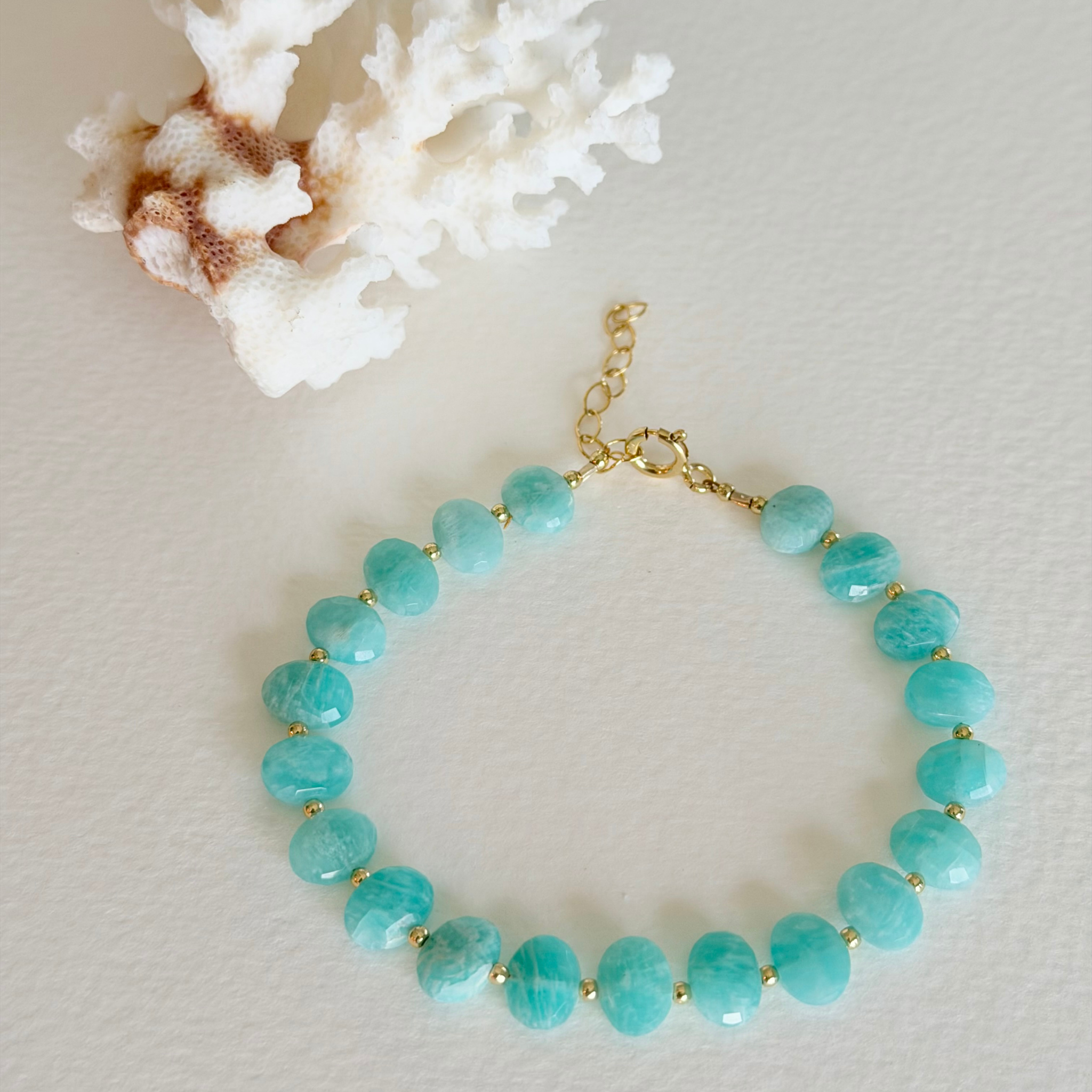 Turquoise beaded bracelet with gold accents on a light background