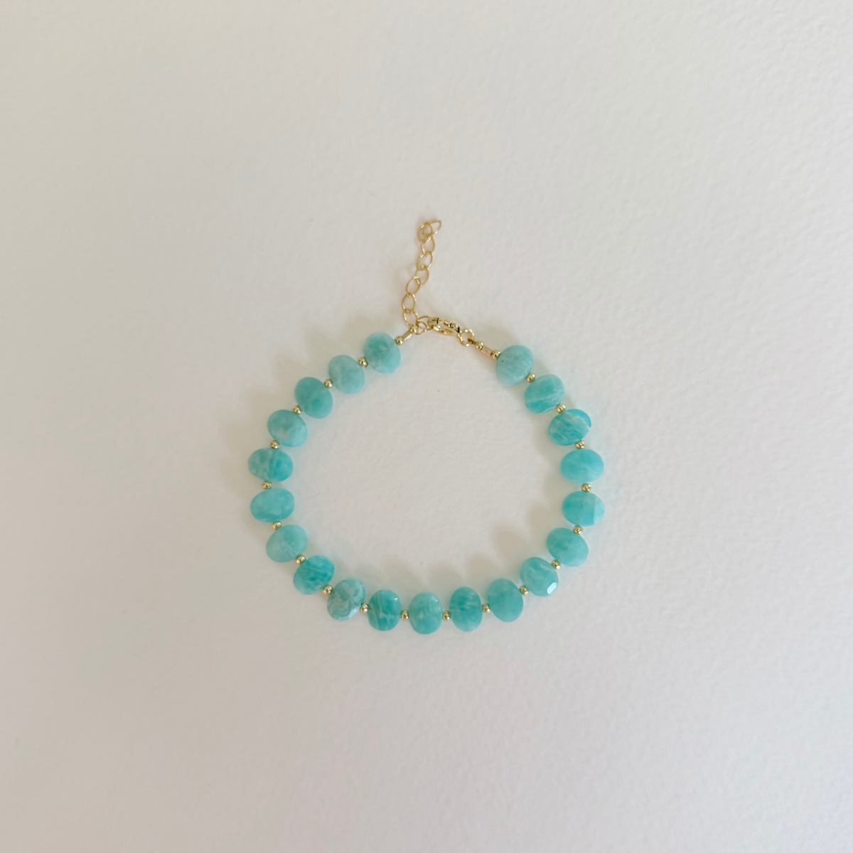 Turquoise beaded bracelet on a gold chain against a white background