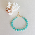 Turquoise beaded bracelet on a light gray background with white coral