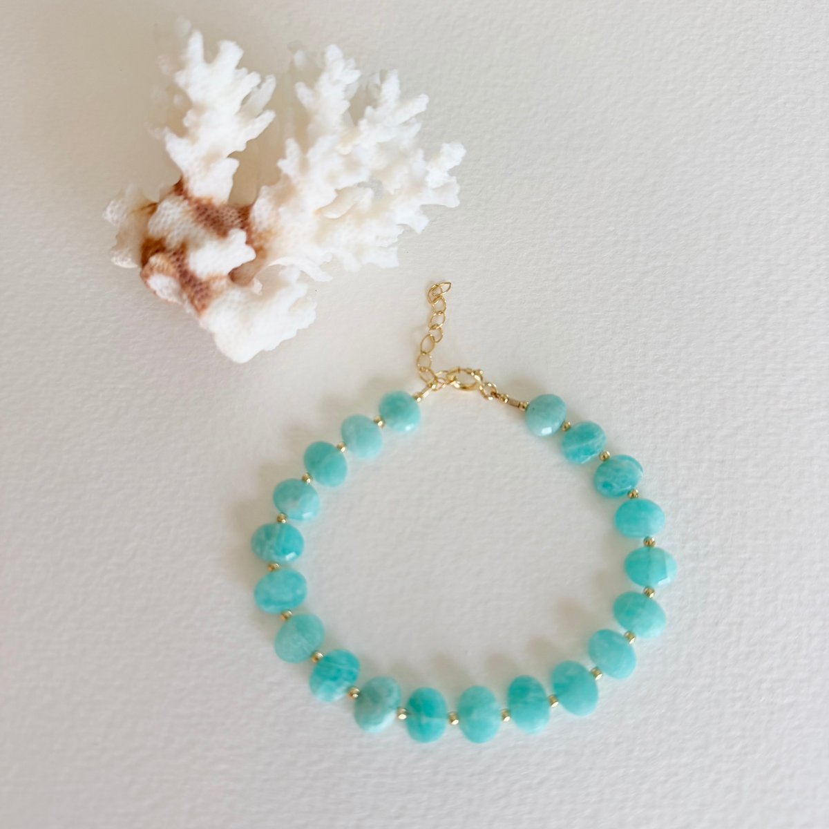 Turquoise beaded bracelet on a light gray background with white coral
